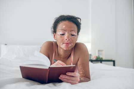 A young woman writing in her diary and looking inspiredの写真素材