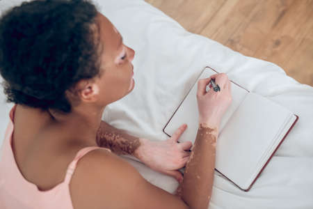 A young woman writing in her diary and looking inspired