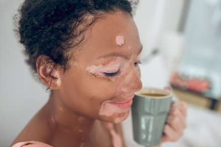 A young woman enjoying her morning herbal tea and smilingの写真素材