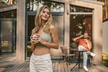 Pretty woman outdoors near home and man behind
