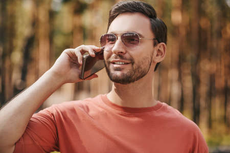 Man in sunglasses with smartphone near earの写真素材