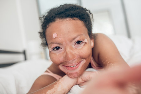 A close up picture of a cute mulatta in bedの写真素材