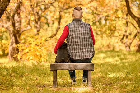 A man sitting on the bench with his dog in the parkの写真素材