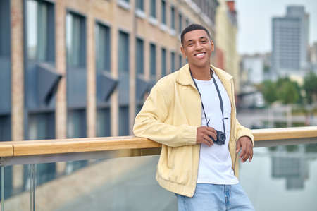 Dark-haired attractive photographer standing on a city background