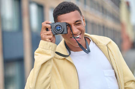 Dark-haired attractive photographer standing on a city background