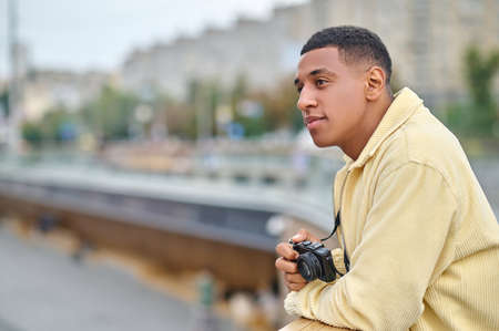 Dark-haired attractive photographer standing with a thoughtful lookの写真素材
