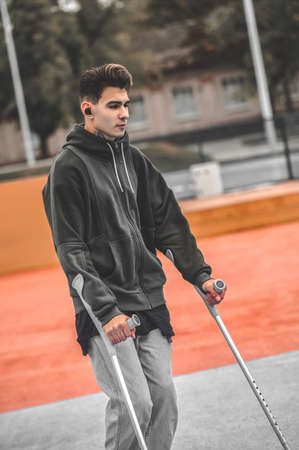 Guy on crutches walking in park