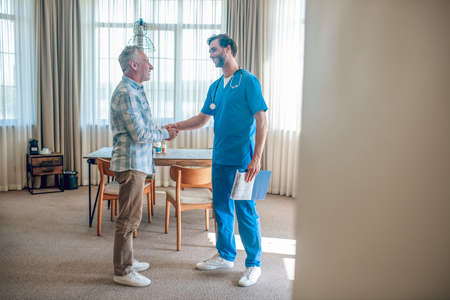 Pleased patient greeting his doctor in his houseの写真素材