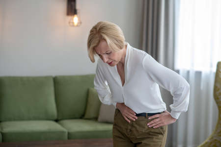 Blond woman feeling bad while suffering from a stomachacheの写真素材