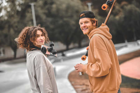 Guy and girl with skateboards turning to cameraの写真素材