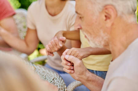 A family holding hands and praying before dinner together