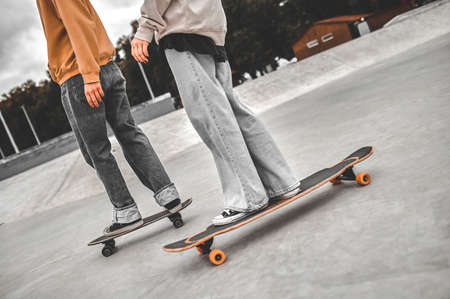 Legs of two young people standing on skateboards