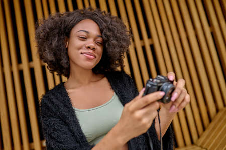 Curly-haired female photographer with camera in handsの写真素材