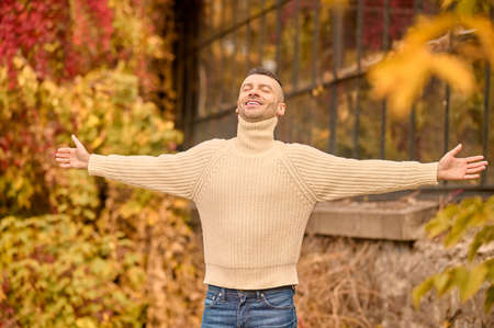 A man in na beige turtleneck in th autumn park