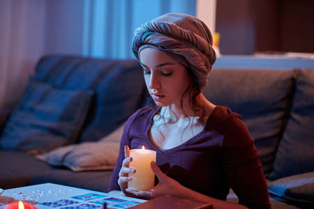 Tranquil soothsayer cleansing her cards with candlelightの写真素材