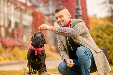 A man with a black dog in the autumn park
