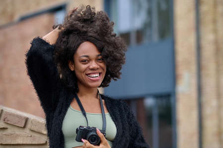 Stylish young woman nesr the browck wall posing and smiling
