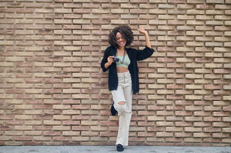 Dark-skinned young woman with camera in the streetの写真素材