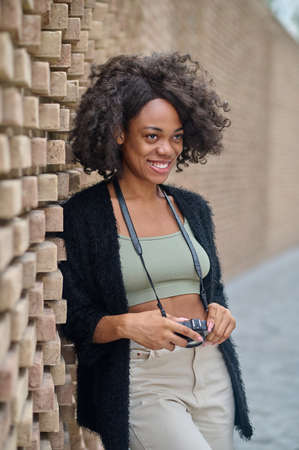 Stylish young woman with camera looking contentedの写真素材