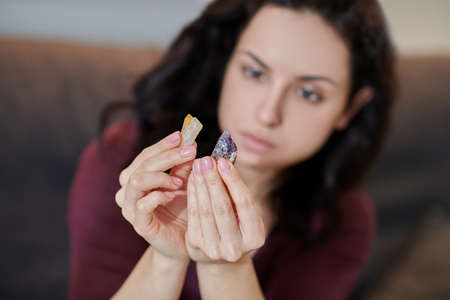 Focused young female scrutinizing citrine and amethystの写真素材