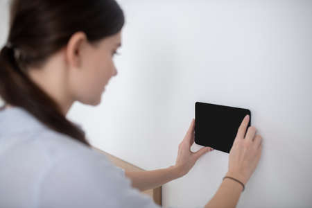 Woman with a ponytail attaching a gadget to the vertical surfaceの写真素材