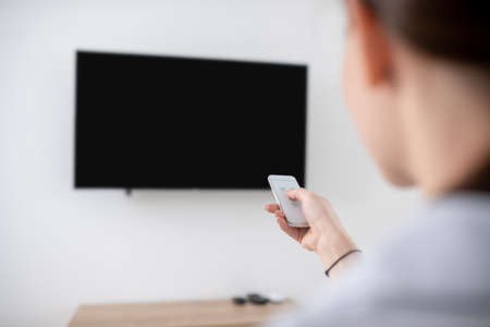 Female turning on the wall-mounted plasma TV