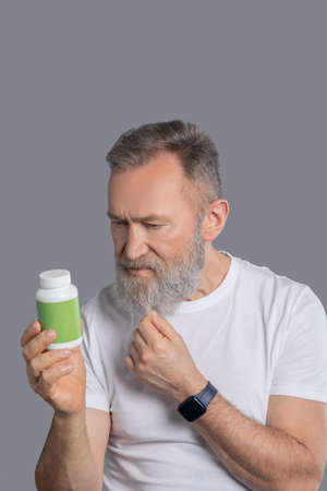 A bearded man holding a jar with vitaminsの写真素材