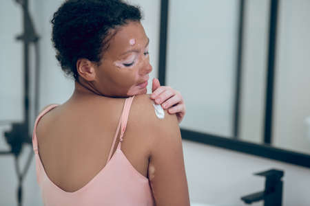 A cute woman applying cream on her body