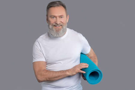 Bearded man holdinga mat for the workoutの写真素材