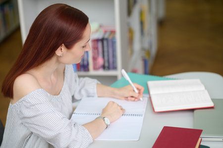 Woman in profile to camera writing at table