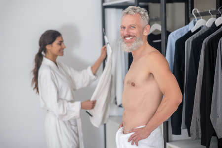 Man looking at camera wife behind choosing shirtの写真素材