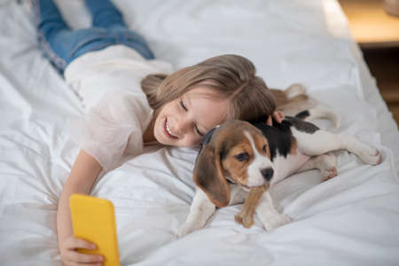 Smiling cute girl making photo with her funny petの写真素材