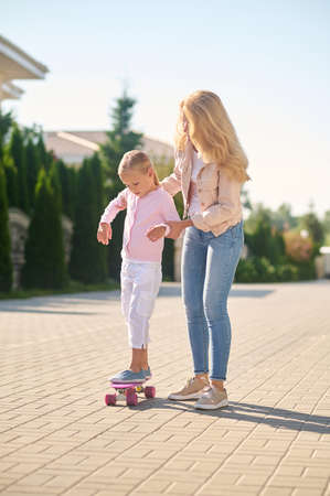 Mom helping her daughter ride a skateboardの写真素材
