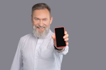 Bearded man with a smartphone in handsの写真素材