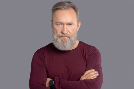 Mature man in burgundy shirt looking seriousの写真素材