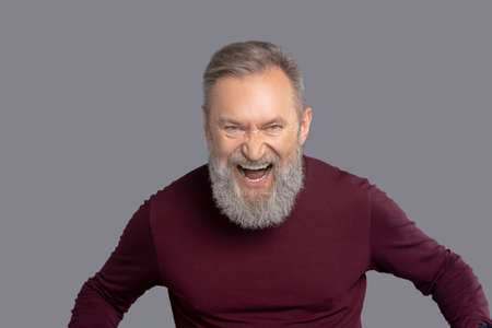 Mature man in burgundy shirt looking excitedの写真素材