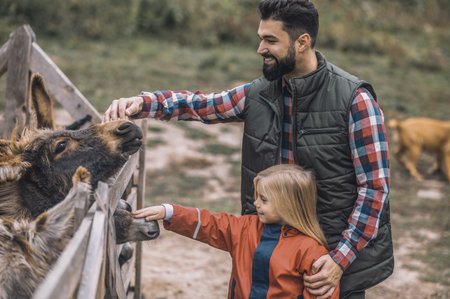 Farmer and a girl standing near the cattle-penの写真素材