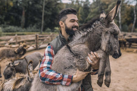 A farmer holding a donkey and smilingの写真素材