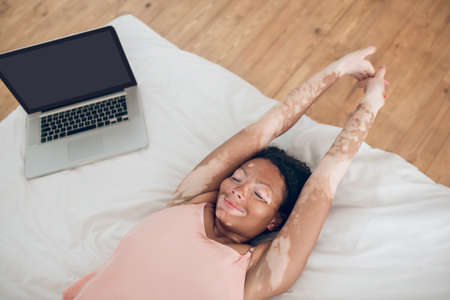 A young woman lying on bed, laptop next to herの写真素材