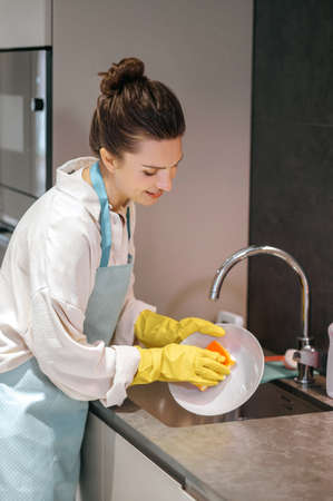 Housewife cleaning the dishes with a sponge and looking involved
