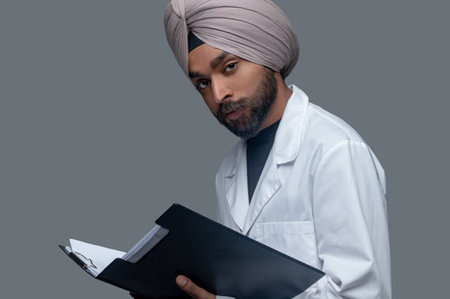 Calm Indian doctor in the turban holding medical documentsの写真素材