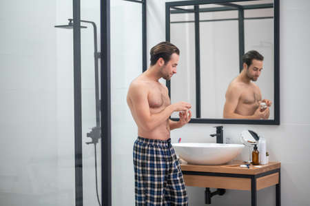 Man in plaid home pants standing at the mirrorの写真素材