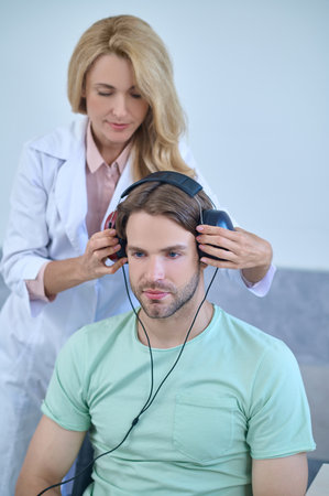 Woman putting on special headphones on patient
