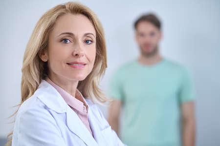 Smiling woman in medical gown looking at cameraの写真素材