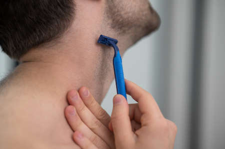 Young man shaving and looking concentratedの写真素材