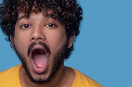 Bearded curly-haired open-mouthed young man looking aheadの写真素材