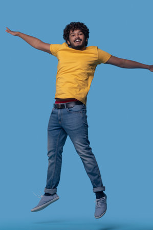 Cute young man with a toothy smile jumping upの写真素材