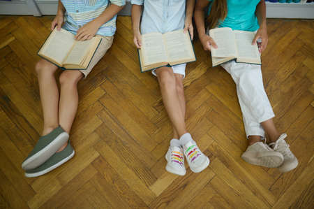 Top view of feet of children reading books on floorの写真素材