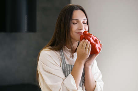 Long-haired young woman holding red pepper in hands