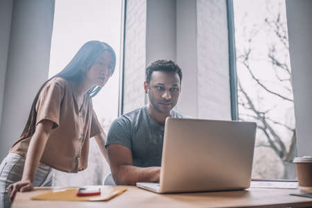 Asian girl and dark-skinned guy looking at laptop